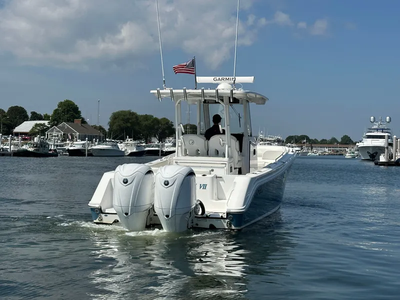 Slide: The Image of 2023 Edgewater 285CC boat with dual engines cruising in a marina under a clear sky. - 3