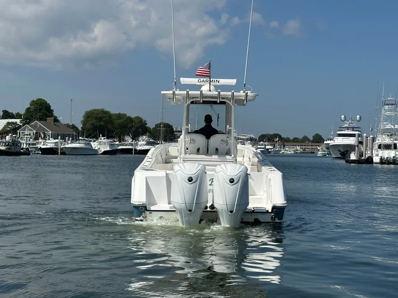 Slide: The Image of 2023 Edgewater 285CC boat cruising in a marina with clear skies. - 4