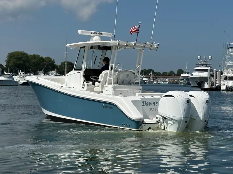 Slide: The Image of 2023 Edgewater 285CC boat with twin engines on a sunny day in a marina. - 5