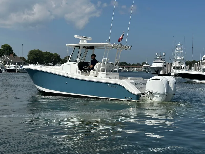 Slide: The Image of 2023 Edgewater 285CC boat cruising in a marina with clear skies. - 6