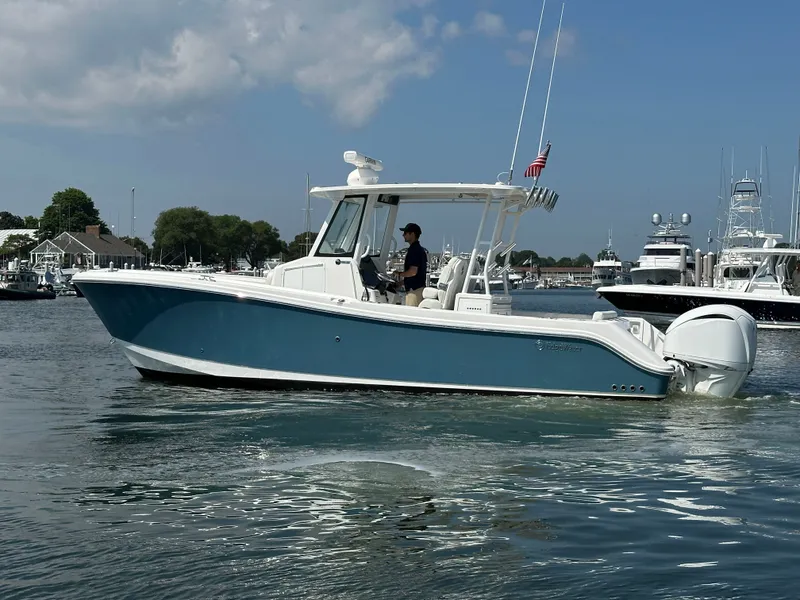 Slide: The Image of 2023 Edgewater 285CC boat cruising in a marina under a partly cloudy sky. - 7