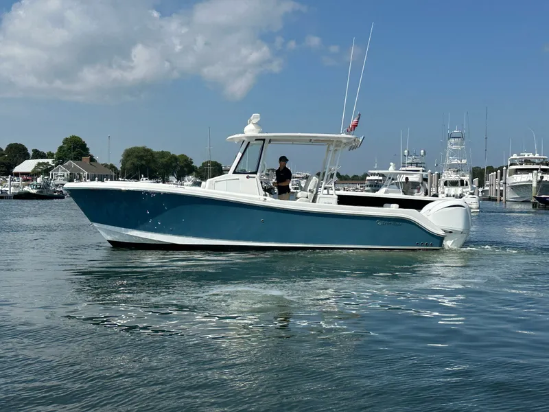 Slide: The Image of 2023 Edgewater 285CC boat cruising in a marina under a clear blue sky. - 8