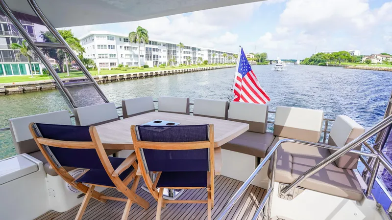 Slide: The Image of Prestige 550 Flybridge 2015 yacht deck with seating, table, and American flag on a sunny day. - 37