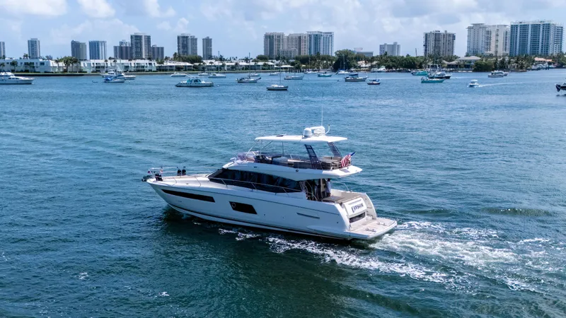 Slide: The Image of 2015 Prestige 550 Flybridge yacht cruising in a scenic coastal cityscape. - 4