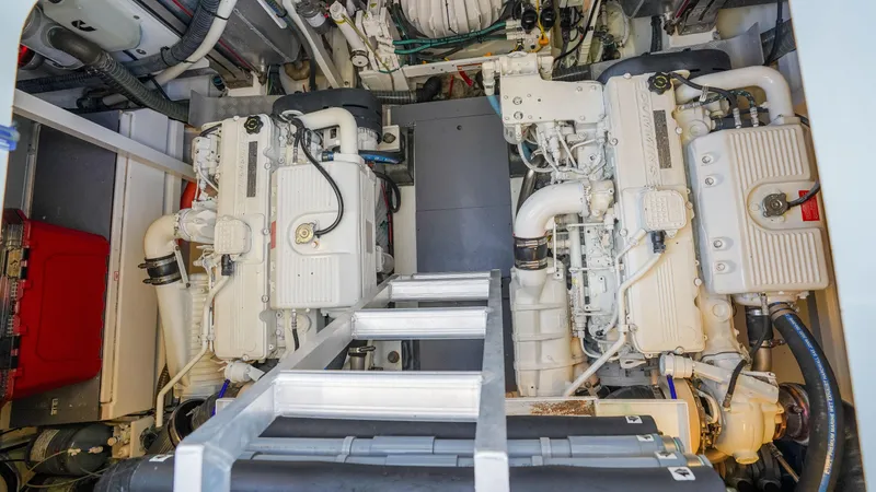 Slide: The Image of Engine room of 2015 Prestige 550 Flybridge yacht, featuring dual white engines and a central ladder. - 46