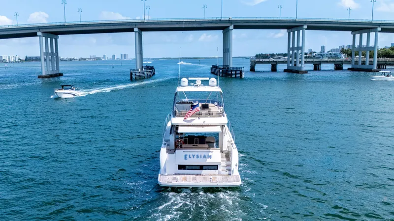 Slide: The Image of Prestige 550 Flybridge yacht cruising under a bridge, 2015 model, with city skyline in background. - 6