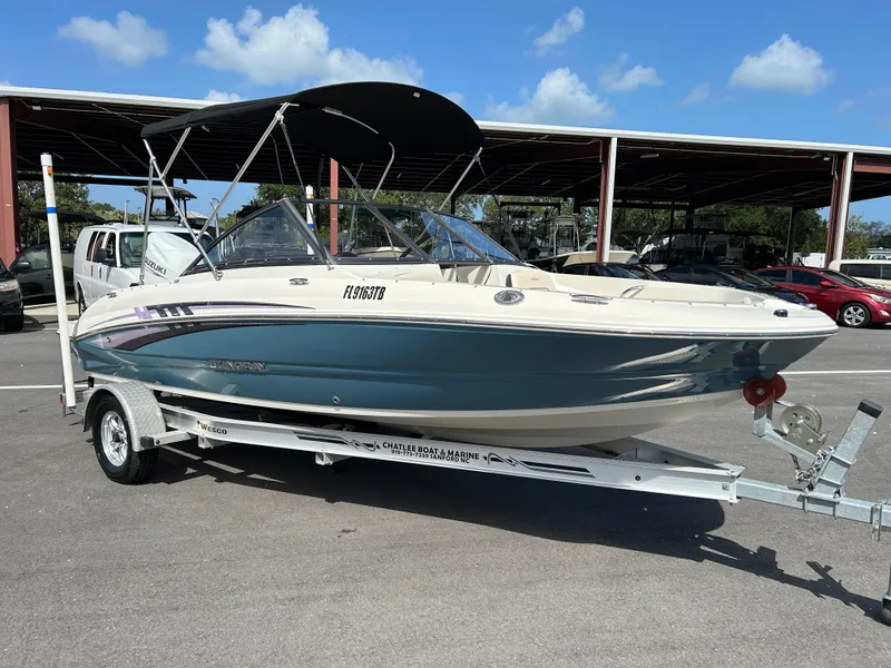 The Image of 2021 Stingray 191 DC boat on trailer, parked outdoors under clear blue sky. - 0