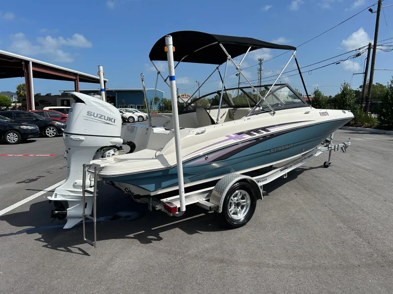 Slide: The Image of 2021 Stingray 191 DC boat with Suzuki outboard motor on a trailer in a parking lot. - 1