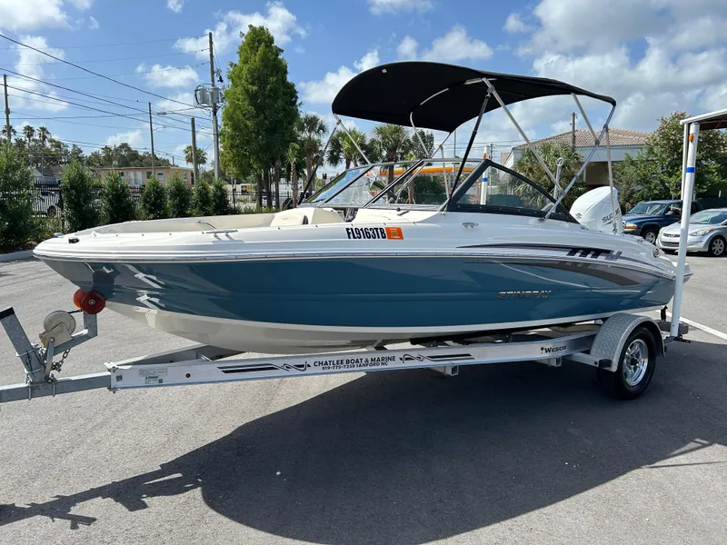 Slide: The Image of 2021 Stingray 191 DC boat on trailer, blue and white, parked outdoors under a clear sky. - 4
