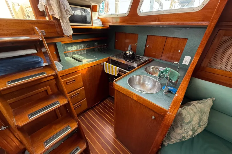 Slide: The Image of 1979 Gulfstar 43 MK II yacht interior with wooden cabinetry and compact kitchen area. - 27