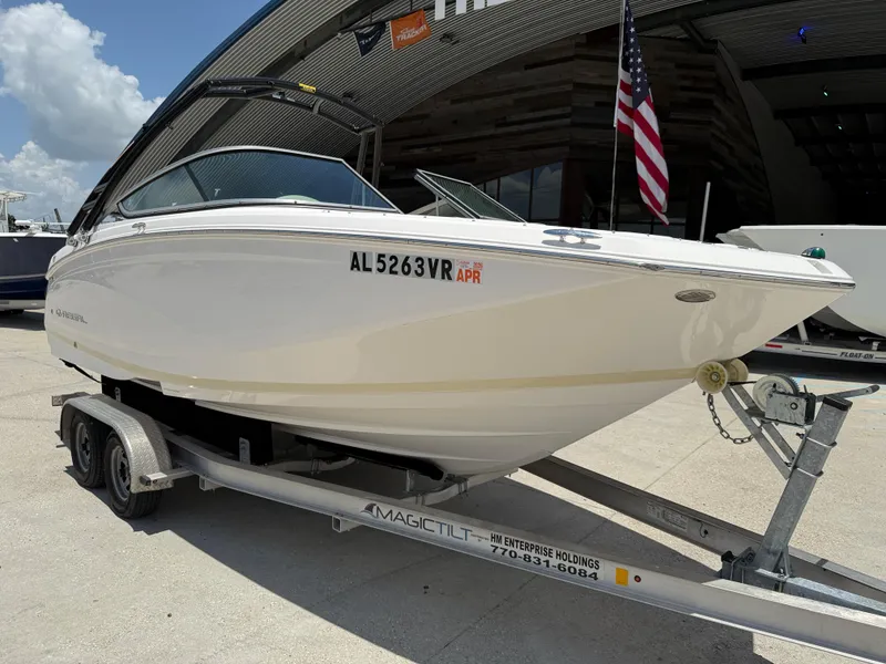 Slide: The Image of 2018 Regal 22 FasDeck boat on trailer, parked outdoors with American flag. - 2