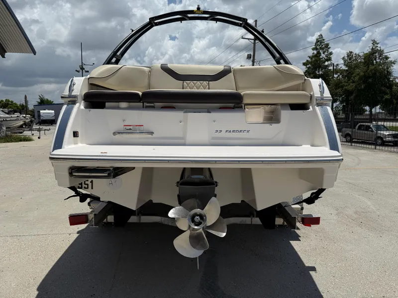 Slide: The Image of 2018 Regal 22 FasDeck boat rear view with propeller, parked outdoors under cloudy sky. - 6