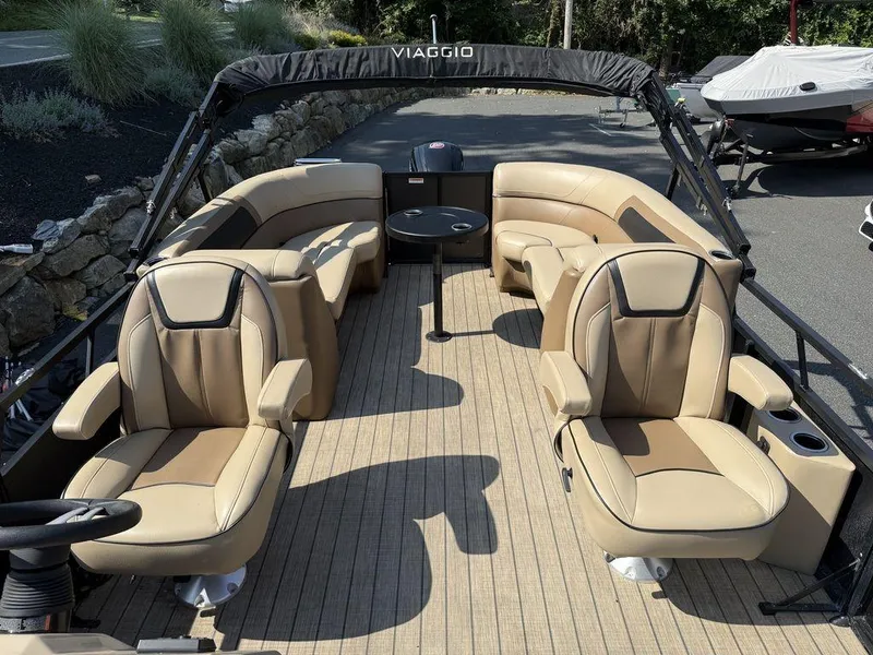 Slide: The Image of Viaggio L22U 2022 boat interior with beige seating and steering wheel, parked outdoors. - 11