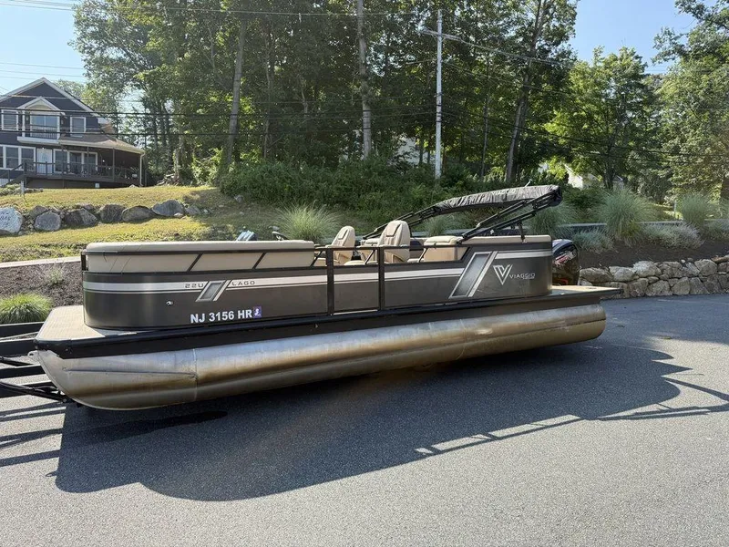 Slide: The Image of 2022 Viaggio L22U pontoon boat parked on a road near a house and trees. - 6