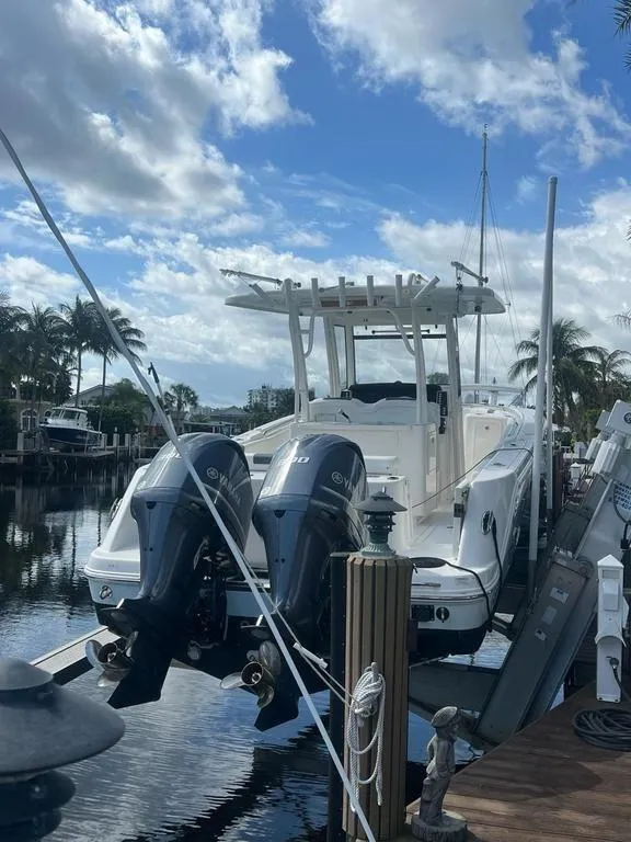 Slide: The Image of 2018 Robalo R302 Center Console boat docked with twin engines, under a partly cloudy sky. - 17