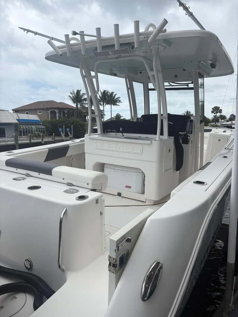 Slide: The Image of 2018 Robalo R302 Center Console boat docked, featuring spacious seating and fishing rod holders. - 20