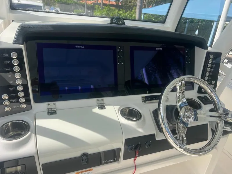 Slide: The Image of 2018 Robalo R302 Center Console helm with dual Simrad displays and chrome steering wheel. - 6