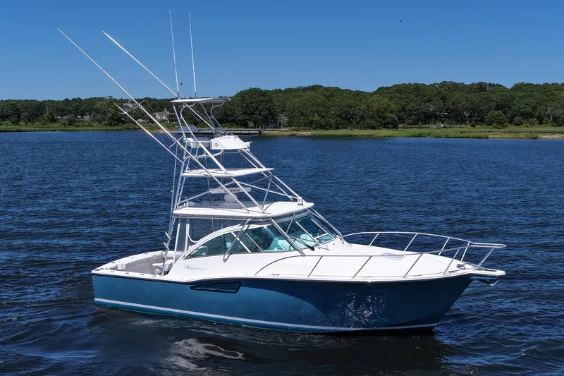 Slide: The Image of 2018 Albemarle 36 Express boat on a calm lake with lush green shoreline. - 15