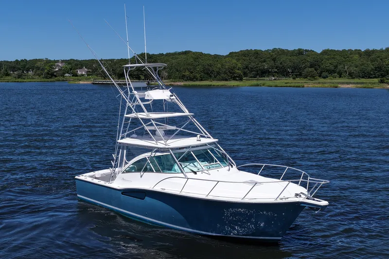 Slide: The Image of 2018 Albemarle 36 Express boat on a calm lake with lush green shoreline. - 16