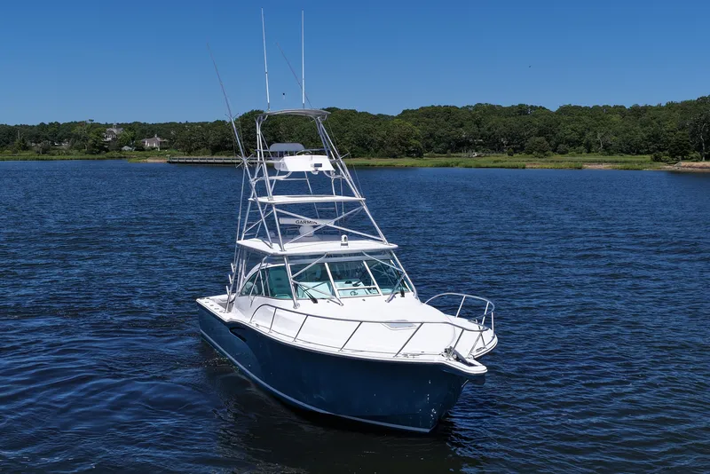 Slide: The Image of 2018 Albemarle 36 Express boat on calm water with lush green shoreline. - 17