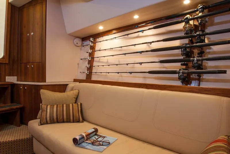 Slide: The Image of Manufacturer Provided Image: Interior of 2018 Albemarle 36 Express with fishing rods, beige sofa, and wooden cabinetry. - 28