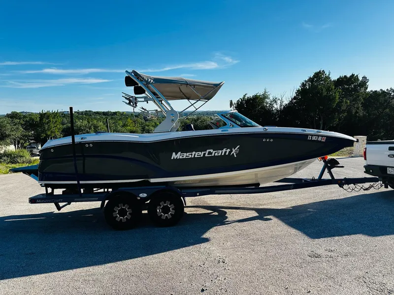Slide: The Image of 2018 MasterCraft X23 boat on trailer, parked outdoors under clear blue sky. - 11