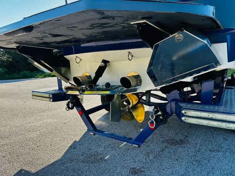 Slide: The Image of 2018 MasterCraft X23 boat stern with propeller and exhaust system, parked on pavement. - 12