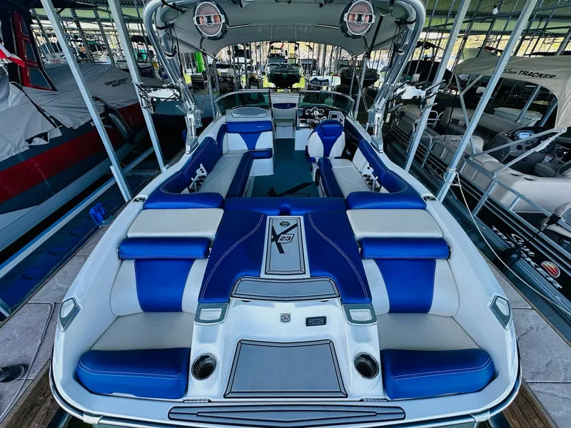 Slide: The Image of 2018 MasterCraft X23 boat with blue and white seating, docked in a marina. - 16