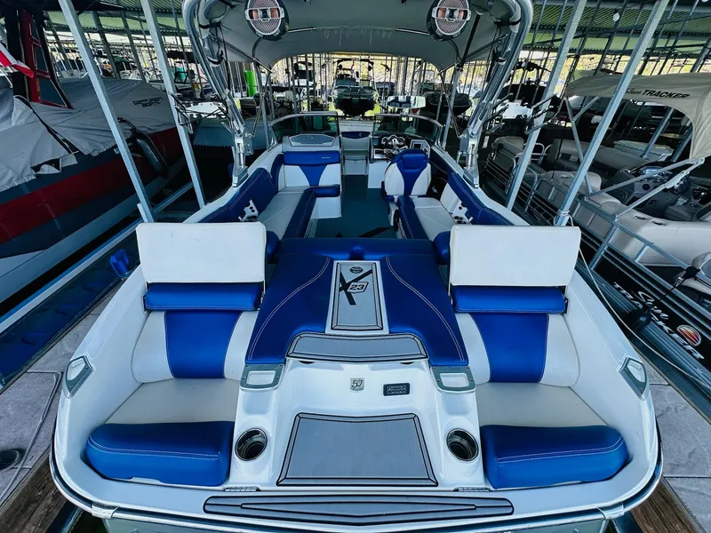 Slide: The Image of 2018 MasterCraft X23 boat interior with blue and white seating, docked in a marina. - 17