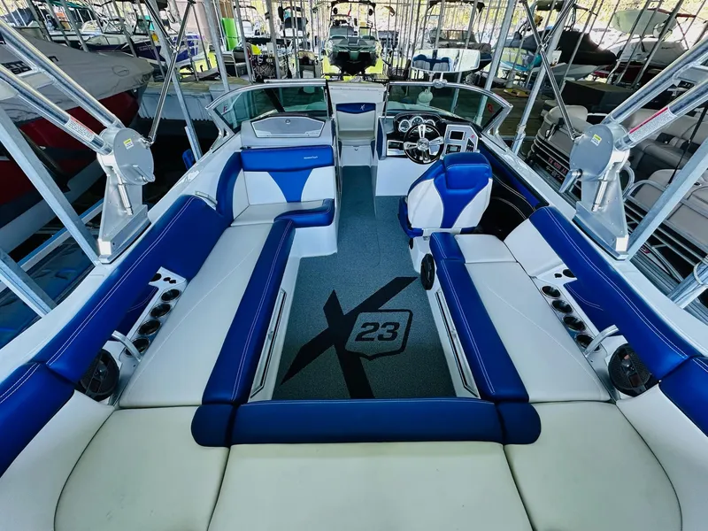 Slide: The Image of 2018 MasterCraft X23 boat interior with blue and white seating, docked in a marina. - 18