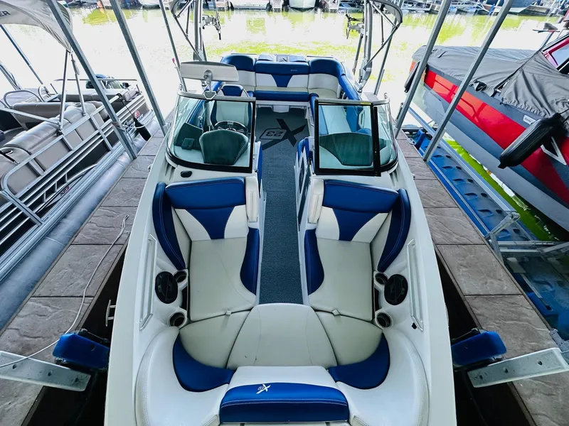 Slide: The Image of 2018 MasterCraft X23 boat with blue and white interior, docked at marina. - 19