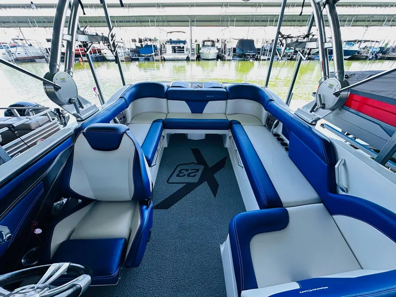 Slide: The Image of 2018 MasterCraft X23 boat interior with blue and white seating, docked at marina. - 20