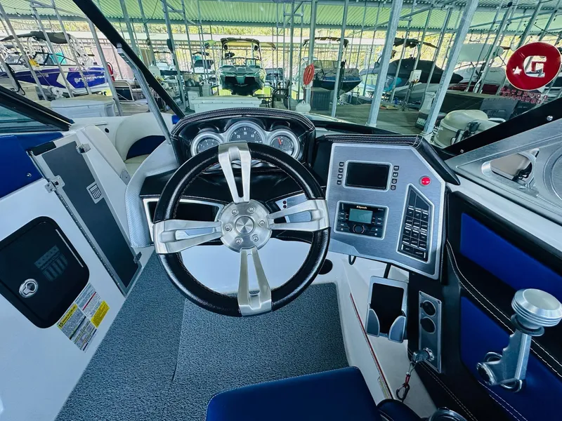 Slide: The Image of 2018 MasterCraft X23 boat dashboard with steering wheel and control panel in marina. - 21