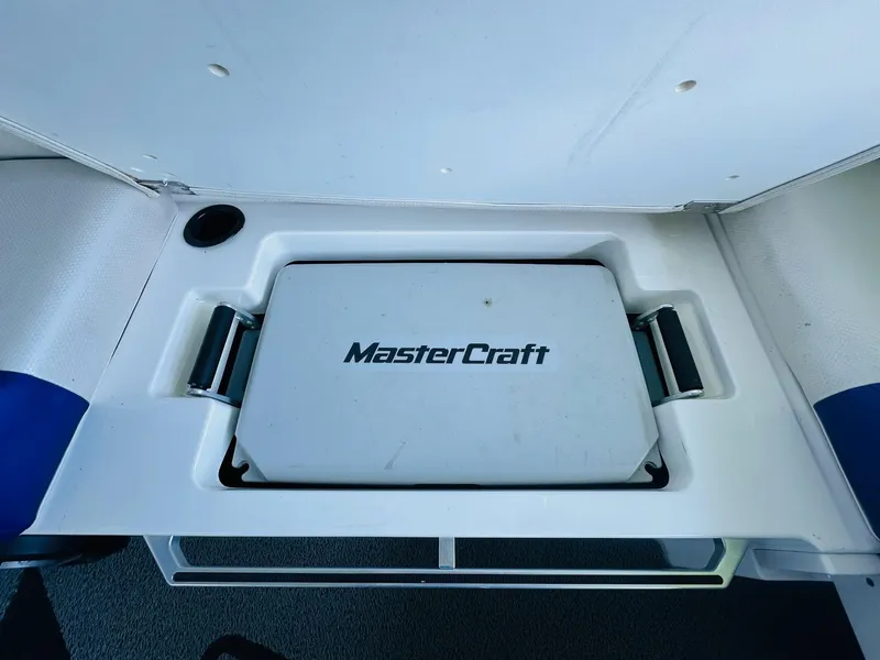 Slide: The Image of 2018 MasterCraft X23 boat storage compartment with logo, white interior. - 23