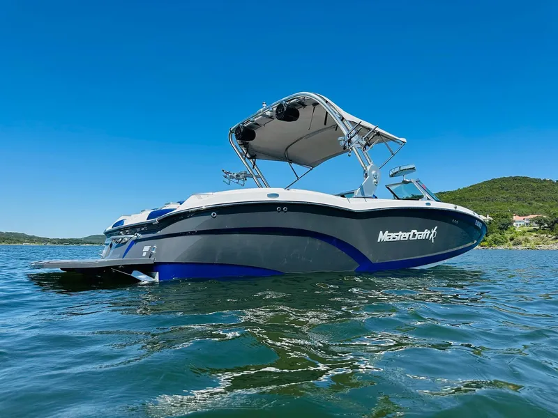 Slide: The Image of 2018 MasterCraft X23 boat on water, clear blue sky, scenic background. - 3