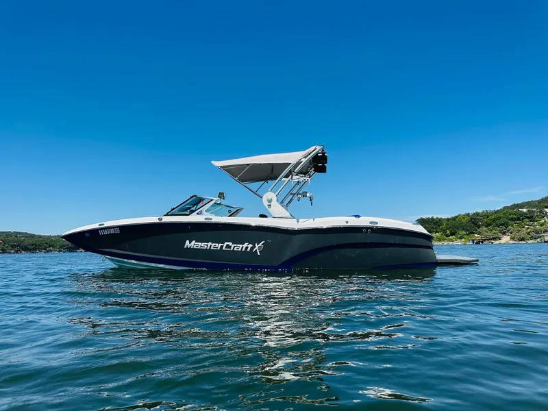 Slide: The Image of 2018 MasterCraft X23 boat on a sunny lake with clear blue skies. - 5