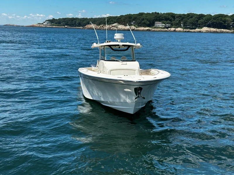 Slide: The Image of 2017 Grady-White Canyon 376 boat on calm blue water near a forested shoreline. - 9