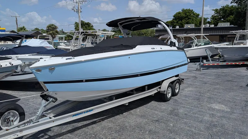 The Image of 2026 Four Winns H6 OB boat on trailer, light blue hull, parked outdoors. - 0
