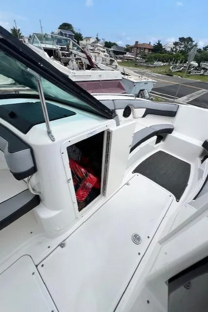 Slide: The Image of 2013 Yamaha Boats 212X interior with open storage compartment, docked at marina. - 12