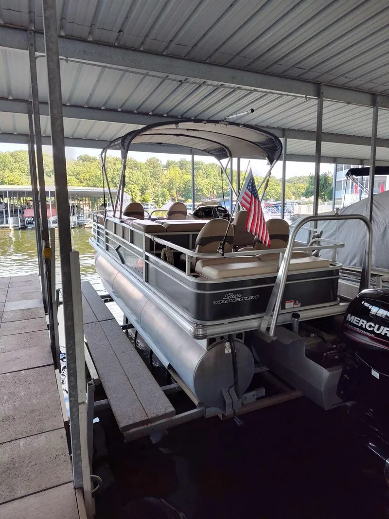 Slide: The Image of 2016 Sun Tracker Fishin' Barge 22 DLX pontoon boat docked under a covered marina. - 2