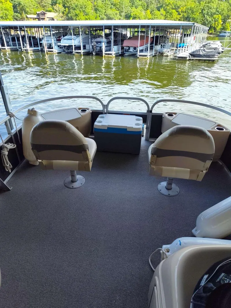 Slide: The Image of 2016 Sun Tracker Fishin' Barge 22 DLX interior with seating and cooler, docked by marina. - 3