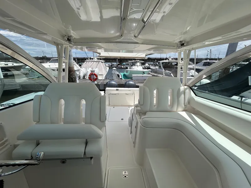 Slide: The Image of 2015 Pursuit DC 325 Dual Console boat interior with white seating and marina view. - 13