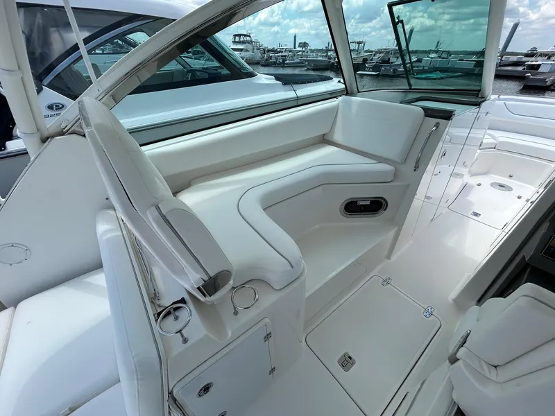 Slide: The Image of 2015 Pursuit DC 325 Dual Console boat interior with white seating and marina view. - 7