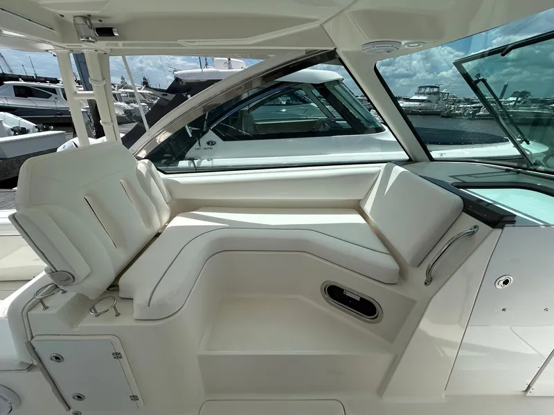 Slide: The Image of 2015 Pursuit DC 325 Dual Console interior with white seating and marina view. - 8