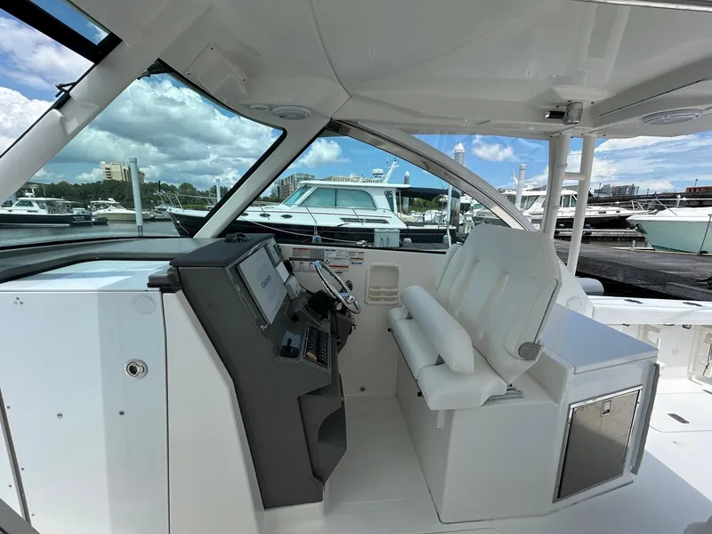 Slide: The Image of 2015 Pursuit DC 325 Dual Console boat interior with helm and seating at marina. - 9