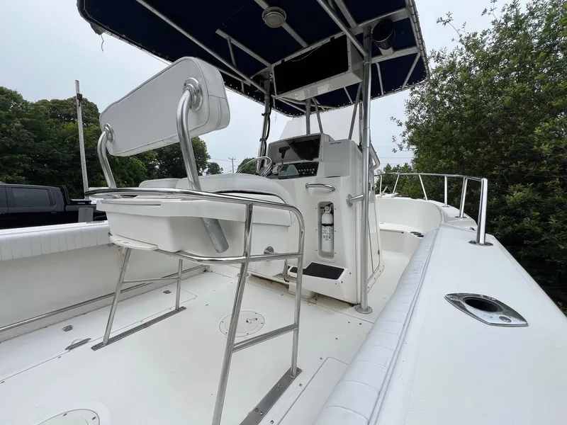Slide: The Image of 2001 Boston Whaler 21 Outrage boat interior with seating and console, surrounded by greenery. - 6