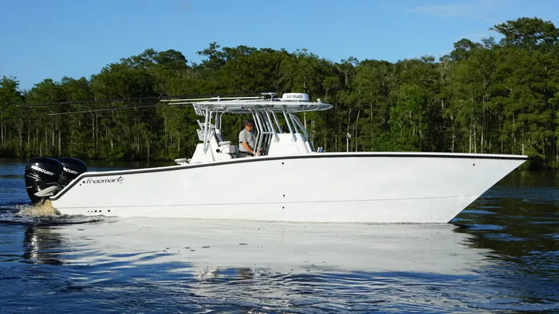 Slide: The Image of 2023 Freeman 34VH boat cruising on a calm river with forested background. - 10