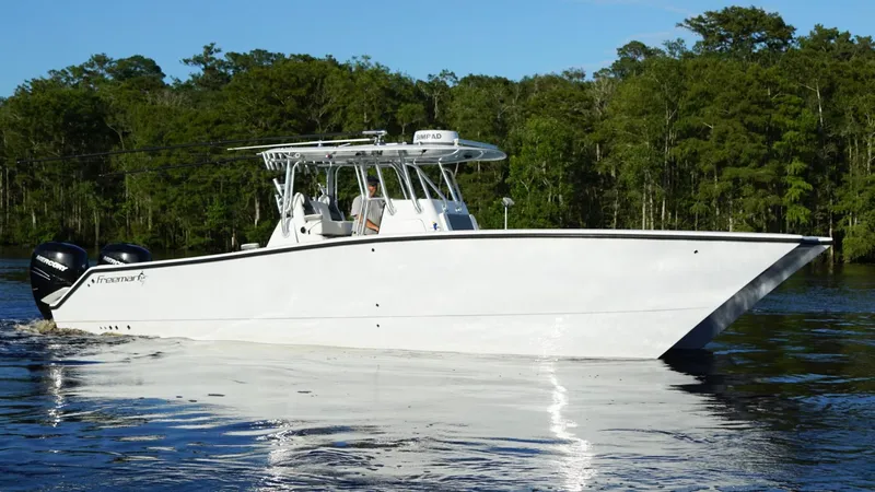 Slide: The Image of 2023 Freeman 34VH boat cruising on a calm river with lush green trees. - 11