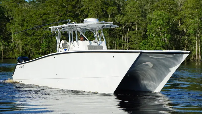 Slide: The Image of 2023 Freeman 34VH boat cruising on a calm river with lush green forest backdrop. - 4