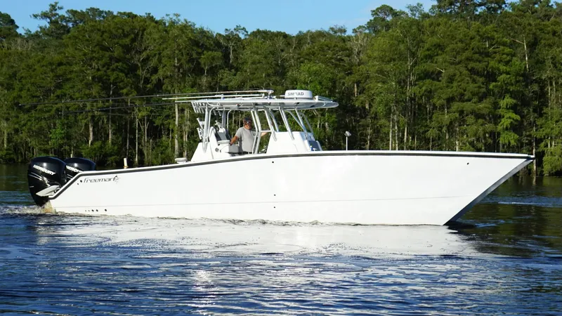 Slide: The Image of 2023 Freeman 34VH boat cruising on a calm river with forested background. - 7